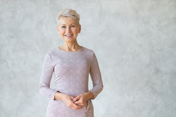 Isolated shot of attractive confident European woman with short haircut posing against textured...
