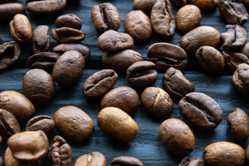 Coffee beans are randomly scattered on a wooden surface in a bar or restaurant. Text space. Close up.