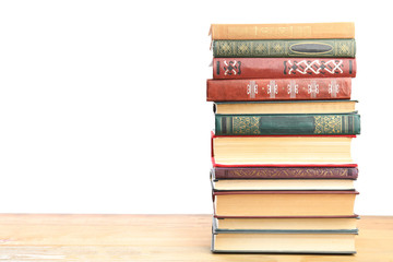 Stack of old vintage books on wooden table against white background