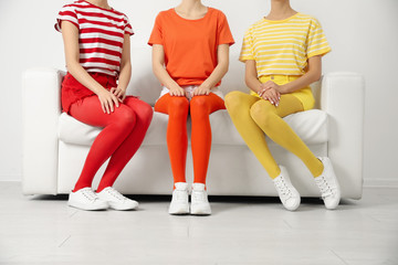 Obraz premium Women wearing bright tights sitting on sofa indoors, closeup
