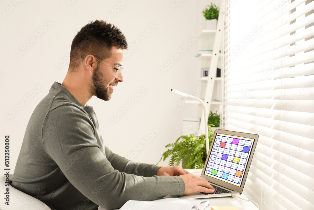 Sticker Young man using calendar app on laptop in office