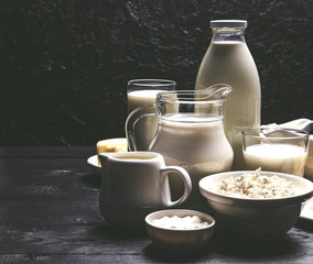 Dairy products on black wooden background, photo filtered in vintage style