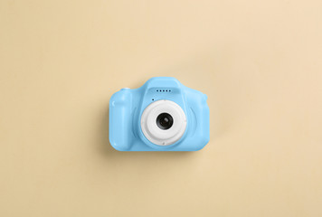 Light blue toy camera on beige background, top view