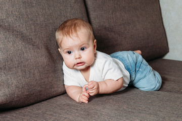 hildhood babyhood and people concept happy smiling little baby boy or girl crawling on sofa