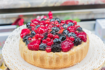 Freshly cooked cheese cake with berries at pastry window shop