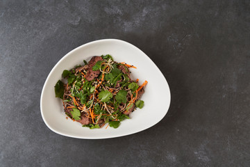 Thai style warm soba salad in white bowl on gray table background