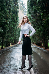 Young business woman in skirt posing outdoors in the rain