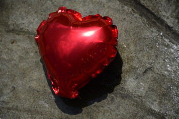 corazón rojo sobre roca y cesped