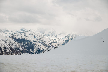 Views of high snow-capped mountain peaks are covered with fluffy white clouds