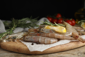 Fresh raw shrimps with lemon slice and rosemary on wooden table