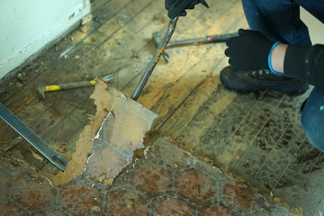 A man taking off old floor in kitchen.