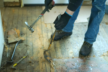 A man working with crowbar and a hammer.