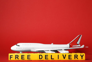Toy plane and cubes with words FREE DELIVERY on red background, space for text. Logistics and...