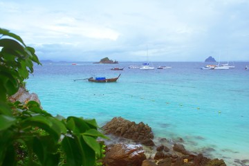 Longtail boats anchored on turquoise waters near the beach of Koh Khai island, Thailand.