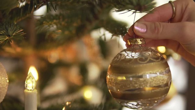 Slow Motion: Hanging golden Christmas bauble on decorated tree, close up
