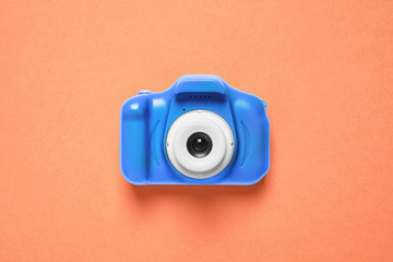 Toy camera on orange background, top view. Color of the year 2020 (Classic blue)