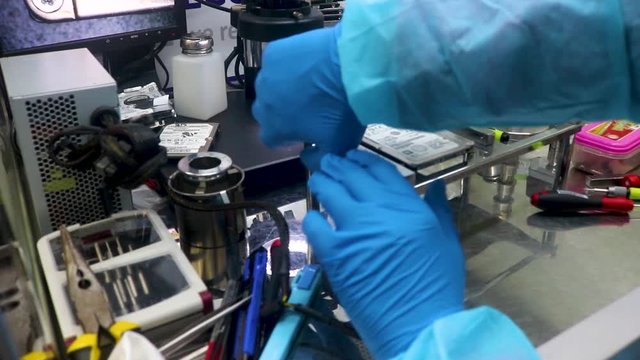 Opening a broken hard drive with a screwdriver at a data recovery center