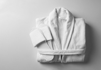 Clean folded bathrobe and slippers on white background, top view