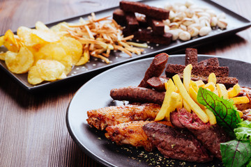 a large plate with a wide selection of snacks for beer on wooden table