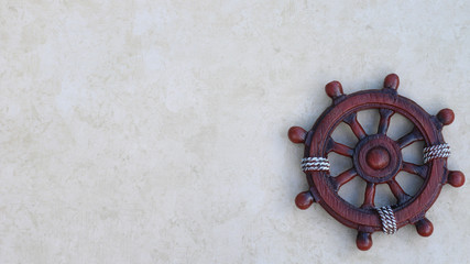 wooden ship wheel isolated on a textured nautical background with writing space