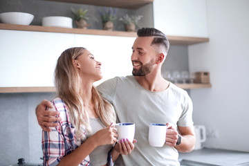 young couple drinking coffee standing in the kitchen