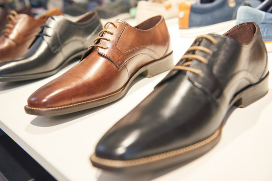 male footwear selling. Formal leather shoes at shelf in shop window
