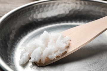 Frying pan with coconut oil and wooden spatula, closeup. Healthy cooking