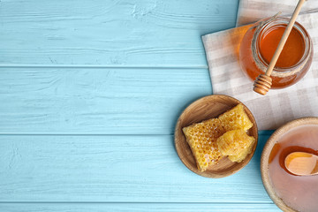 Flat lay composition with delicious honey on blue wooden table. Space for text