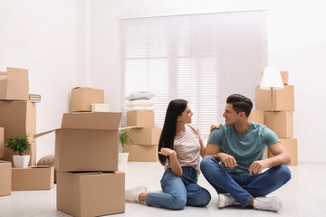 Happy couple in room with cardboard boxes on moving day