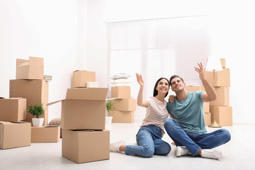 Happy couple in room with cardboard boxes on moving day