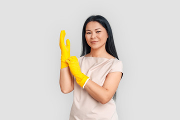 Freestyle. Asian woman putting on gloves standing isolated on white posing to camera confident