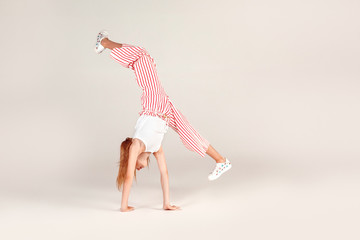 Obraz premium Inclusive Beauty. Girl with red hair isolated on grey doing front walkover concentrated