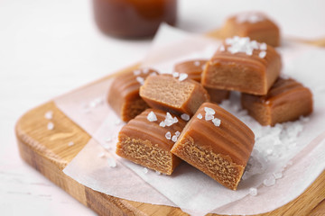 Delicious salted caramel on wooden board, closeup