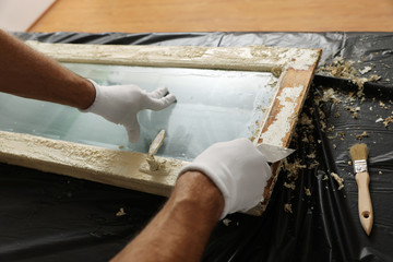Man repairing old damaged window at table indoors, closeup