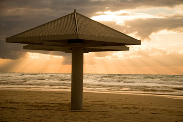 A beach at sunset with a parasol