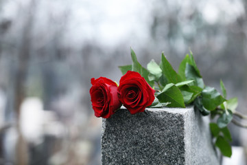 Red roses on grey granite tombstone outdoors. Funeral ceremony - obrazy, fototapety, plakaty