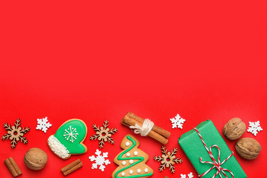 Flat lay composition with Christmas decorations and treats on red background, space for text. Winter holidays