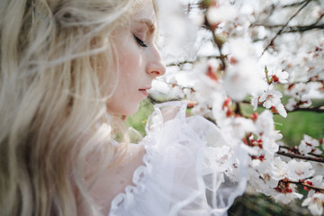 Naklejka premium beautiful young woman with long blonde hair in blossom park