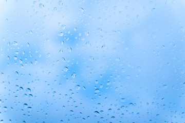 Raindrops on glass against blue sky