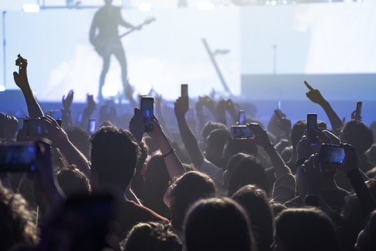  people having fun and dancing with their hands to the sky during a live music concert