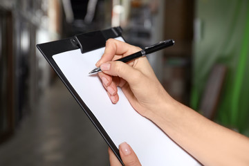 Woman with clipboard in wholesale warehouse, closeup