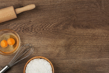 Flat lay composition with raw eggs and other ingredients on wooden table, space for text. Baking pie