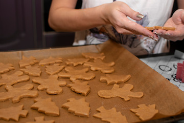 female hands spread Christmas cookies on a baking sheet to bake. Selective focus