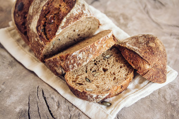 Brown fresh bread with seeds are cut into pieces on old wood background. Copy, empty space for text