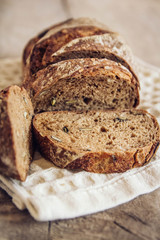 Brown fresh bread with seeds are cut into pieces on old wood background. Copy, empty space for text