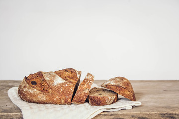 Brown fresh bread with seeds are cut into pieces on old wood background. Copy, empty space for text