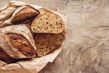 Brown fresh bread with seeds are cut into pieces on old wood background. Copy, empty space for text