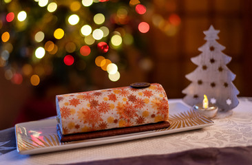 Yule log roll cake for Christmas decorated with magnificent patterns with a colorful bokeh background.