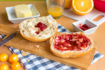 Fototapeta na wymiar knackige Frühstücksbrötchen mit Marmelade. Dazu leckere Physalis und frischen Orangensaft