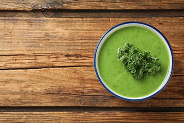 Tasty kale soup on wooden table, top view. Space for text